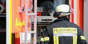 Feuerwehrmann in Montur vor Feuerwehrauto