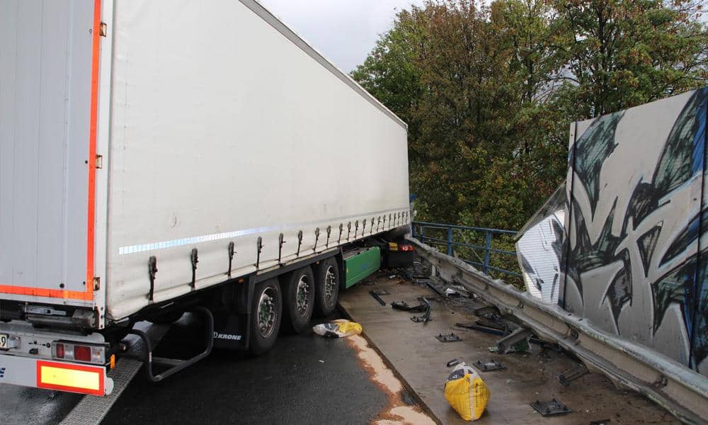 LKW nach Unfall in beschädigter Lärmschutzwand