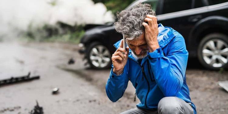 Mann telefoniert nach einem Autounfall