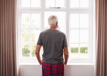 Mann mit grauen Haaren schaut aus dem Fenster