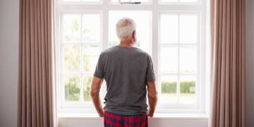 Mann mit grauen Haaren schaut aus dem Fenster