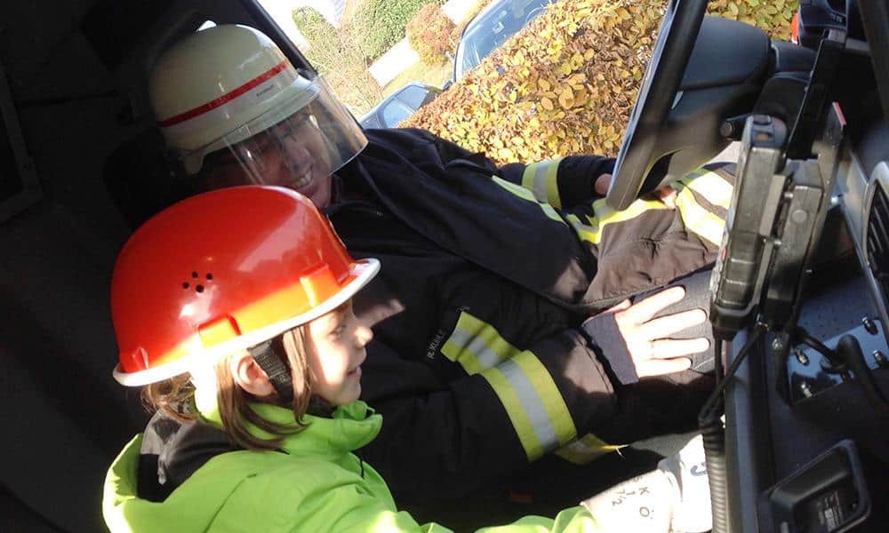 Ein tolles und lautes Team: Die 6jährige Jamie und Landrat Jürgen Müller lösen im Feuerwehrlaster gemeinsam die Sirene aus. - © Kreis Herford